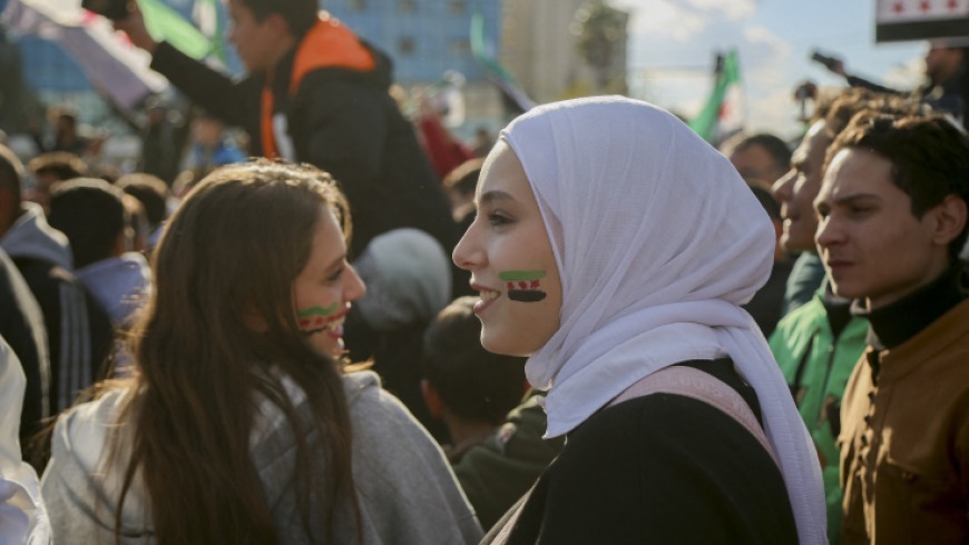 From a Lattakia Governor’s Circular to a Broader Policy Pattern: Women in the Transitional Phase Under Scrutiny Syria TV A circular issued by the Governor of Lattakia banning female employees from wearing makeup during official working hours has triggered widespread debate. Critics view the measure as an intrusion into women’s personal choices and a test of how far local authorities may go during the transitional phase. More broadly, it has revived questions about whether current decision-making aligns with the principles of equality and non-discrimination that are meant to guide state reconstruction. While some officials described the circular as a routine administrative step, activists and legal experts argue that its significance lies in a broader pattern: decisions that directly affect women are issued without their participation, without meaningful representation in positions of influence, and without adequate consideration of their legal, social, or economic impact. Disputed Authority Lawyer Soufana Khalil told Syria TV that the circular is “illegal,” issued without jurisdiction or legal basis. She said it violates the constitutional declaration for the transitional phase, entails gender-based discrimination, and infringes on personal freedom and human dignity. Khalil argued that the measure is legally void and open to challenge, and that no administrative penalties may be imposed under it. Although temporary constitutional texts affirm equality and non-discrimination, she noted that these principles remain ineffective without clear enforcement and oversight mechanisms. Their absence, she warned, enables local decisions that contradict the spirit of equality without meaningful accountability. Women and Decision-Making Feminist activist Hiyam Haj Ali described women’s representation in transitional institutions as “embarrassingly low.” Previous efforts aimed to secure at least 30 percent representation to ensure women’s participation in public debate and policymaking. The results so far, she said, fall short of those commitments. She argued that excluding women from decision-making weakens political life, undermines institutional legitimacy, and marginalises women’s needs in legislation and policy. Women’s representation in the People’s Assembly, she noted, was left to presidential discretion rather than embedded in binding electoral rules, turning representation into a matter of political will rather than a guaranteed right. The head of the elections committee, Mohammad Taha al-Ahmad, attributed women’s “limited” participation to prevailing social customs. Observers counter that framing the issue as cultural alone risks excusing the absence of structural remedies such as quotas or political empowerment programmes. Activists say this reflects an approach that treats women’s participation as a file managed from above rather than a legal entitlement. Data from the Karam Shaar Advisory and Studies Center show that women constitute only 4.9 percent of elected members (6 out of 122), down from 11.2 percent in the 2020 parliament. Women made up just 14.1 percent of candidates. The center cited entrenched social barriers and procedural flaws, noting that the Higher Elections Committee included only two women among eleven members and that candidate-selection bodies were overwhelmingly male. From Policy to Practice Administrative measures that marginalise women extend beyond symbolic control of appearance. They contribute to pushing women out of the formal labour market and limiting access to stable income and economic independence. In a context where many women are heads of household after years of war, hostile work environments risk deepening vulnerability rather than supporting recovery. Doaa, a former employee, said workplace pressures have intensified. “When my temporary contract ended, I chose not to renew it. The psychological and professional pressure became unacceptable,” she said. Salma, who supports her family, now works in unstable conditions in a local market. “This exclusion systematically reproduces poverty and places me under double pressure,” she explained. Leila left institutional work after enduring scrutiny and comments about her clothing, opting instead for less stable independent work. Legal Restrictions Beyond the Workplace Controversy has also surrounded Circular No. 17 of 2025 issued by the Ministry of Justice, which critics say limits a mother’s independence in managing her children’s affairs. Hajar said the measure revived fears she believed she had overcome and made her reconsider returning to Syria. Instead of strengthening justice, she argued, such texts risk placing women’s rights under discretionary authority. A Broader Pattern Studies indicate that Syrian women face intersecting legal, social, and economic vulnerabilities in the post-regime period, affecting education, employment, and mental health. Weak legal protections and limited access to formal work continue to push many into informal sectors with unstable wages and few safeguards. Taken together, the Lattakia circular and similar measures suggest more than isolated incidents. They point to an unsettled question at the heart of the transitional phase: whether women will be treated as full citizens with guaranteed rights, or whether old imbalances will reappear in new forms.